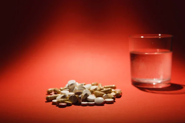 药物白色彩色片剂安排抽象在深红色背景。胶囊玻璃瓶的水丸设计。健康治疗选择健康的生活方式观念。复制空间广告. — 图库照片