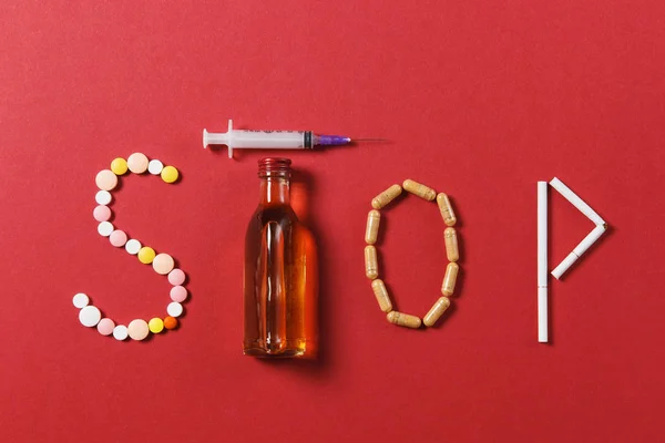 Gyógyszert fehér kerek tabletta, a Stop szó. Kreatív összetétele üzenetet hagyja abba inni üveg alkohol üres fecskendő tűvel a fekete háttér. Choice, egészséges életmód fogalma. — Stock Fotó