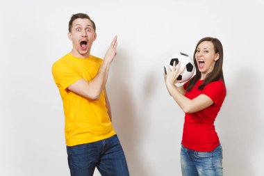 Eğlenceli çılgın Avrupa Genç çift, kadın, erkek, beyaz arka plan üzerinde izole sarı kırmızı üniforma tutun oyun futbol topu futbol taraftarları. Spor, oyun futbol, Aile Eğlence, yaşam kavramı.