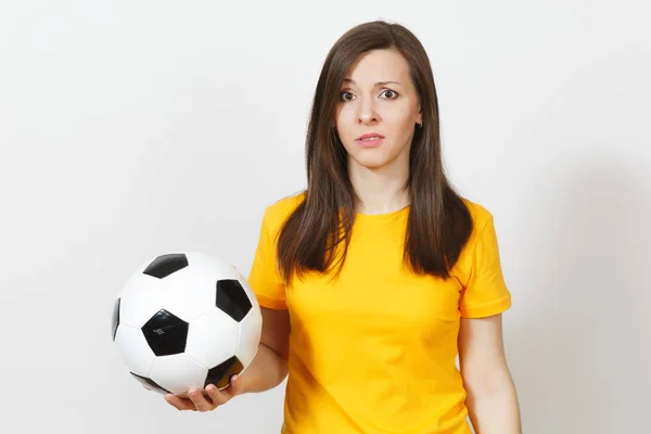Bastante europeo joven triste mujer molesta, fanático del fútbol o jugador en uniforme amarillo sostiene pelota de fútbol, se preocupa por perder equipo aislado sobre fondo blanco. Deporte, fútbol, concepto de estilo de vida . — Foto de Stock