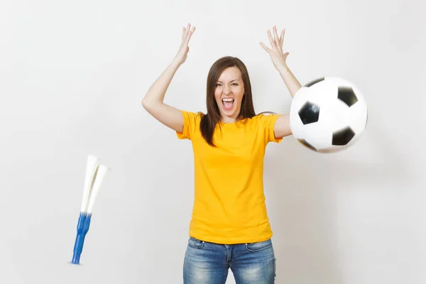 Beautiful European young cheerful happy woman, soccer fan or player in yellow uniform throwing football pipe, ball isolated on white background. Sport play football, health, healthy lifestyle concept.