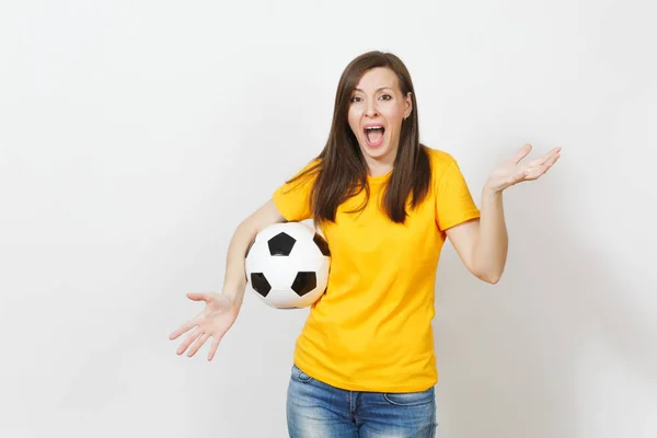 Bella giovane donna urlante arrabbiato europeo, tifoso di calcio o giocatore in uniforme gialla tenendo palla da calcio isolato su sfondo bianco. Sport, calcio, salute, stile di vita sano . — Foto Stock