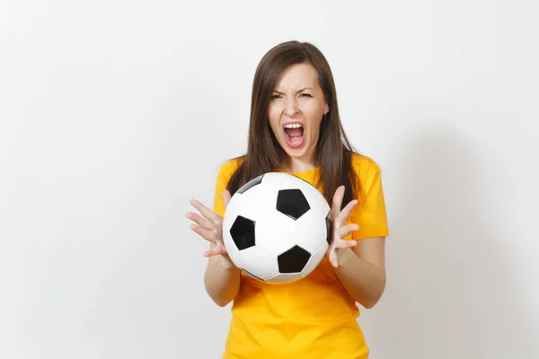 Bella giovane donna urlante arrabbiato europeo, tifoso di calcio o giocatore in uniforme gialla tenendo palla da calcio isolato su sfondo bianco. Sport, calcio, salute, stile di vita sano . — Foto Stock