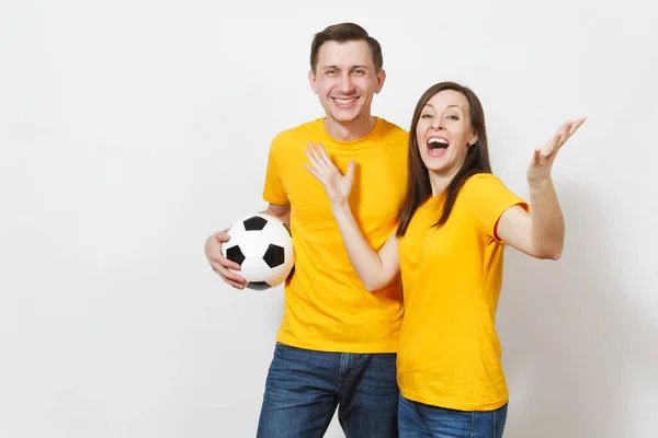 Diversión loca alegre joven pareja emocional, mujer, hombre, aficionados al fútbol en uniforme amarillo animar equipo de apoyo con pelota de fútbol aislado sobre fondo blanco. Deportes, ocio familiar, concepto de estilo de vida . —  Fotos de Stock