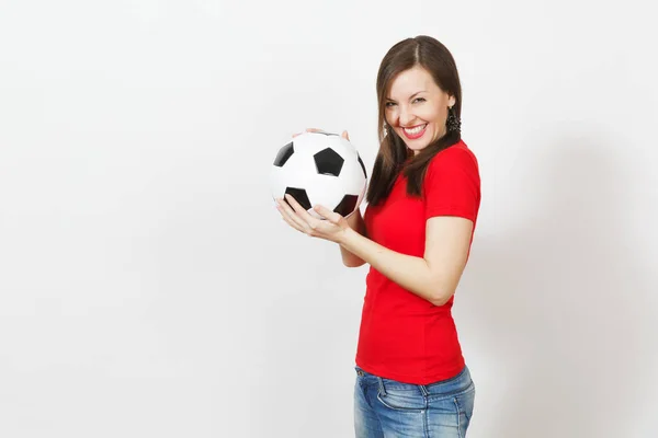 Joven europea sonriente, dos divertidas colas de caballo, fanático del fútbol o jugador en uniforme rojo sosteniendo la clásica pelota de fútbol aislada sobre fondo blanco. Deporte jugar fútbol salud, concepto de estilo de vida saludable . — Foto de Stock