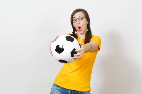 Divertente allegra donna europea, due code di cavallo, tifoso di calcio o giocatore in occhiali, uniforme gialla tenere classico pallone da calcio isolato su sfondo bianco. Sport, gioco, calcio, stile di vita sano . — Foto Stock