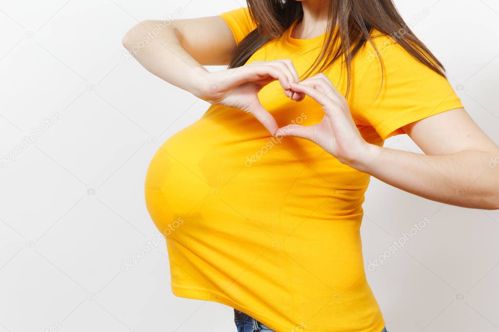 Close up cropped woman football fan or player with soccer ball under yellow uniform as pregnant with big belly isolated on white background. Sport play football, health, healthy lifestyle concept.
