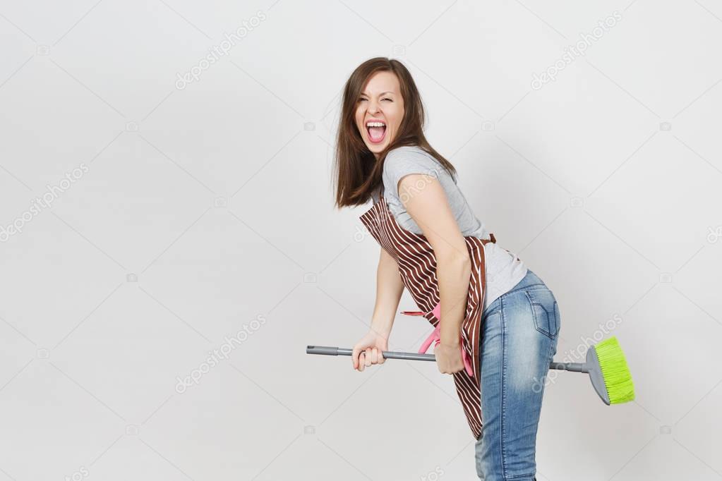 Young fun crazy dizzy loony wild screaming housewife with tousled hair in striped apron, squeegee in pocket isolated on white background. Mad witch woman flying on broom. Copy space for advertisement.