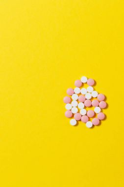 İlaç beyaz renkli yuvarlak tabletler sarı renk arka plan üzerinde soyut düzenlenmiştir. Aspirin, tasarım hapı kullanmaya başladı. Sağlık, tedavi, sağlıklı yaşam kavramı. Kopyalama alanı reklam.