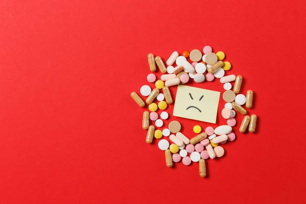 Het kleurrijke ronde tabletten medicatie witte geregeld abstract op rode kleur achtergrond. Aspirine, capsule pillen, papieren sticker vellen, triest glimlach gezicht. Beroep, behandeling, keuze gezonde levensstijl concept. — Stockfoto