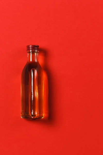 Flaska med alkohol på röd bakgrund. Hälsa, drink, val, hälsosam livsstilskoncept. Kopiera utrymme för annonseringen. Med plats för text. — Stockfoto