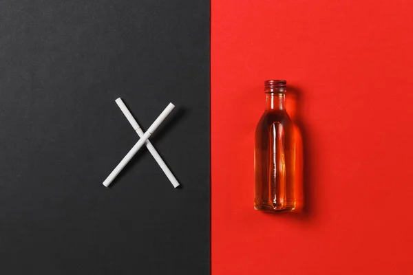 Två korsade vita cigaretter som bokstaven X, flaska med alkohol cognac, whiskey på svart röd bakgrund. Hälsa, val, hälsosam livsstilskoncept. Kopiera utrymme för annonseringen. Med plats för text. — Stockfoto
