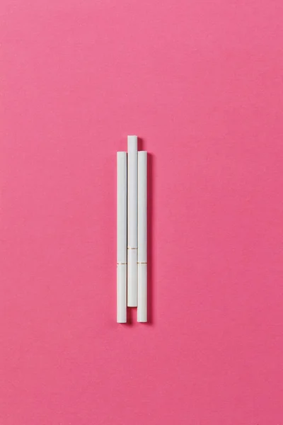 Три білі сигарети на фоні рожевої троянди. Здоров'я, вибір, концепція здорового способу життя. Копіювати простір для реклами. З місцем для тексту . — стокове фото