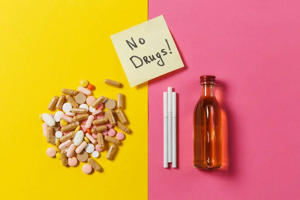 カラフルな薬錠配置薬概要、ボトル アルコール、黄色ピンク バラ背景にタバコ。紙ステッカー シート テキストの単語ない薬。治療、健康的なライフ スタイルの選択。コピー スペース. — ストック写真
