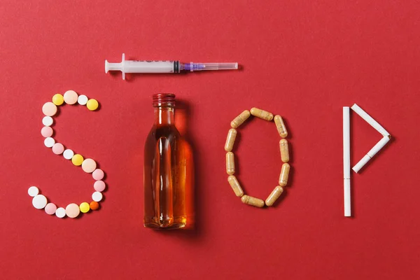 Gyógyszert fehér kerek tabletta, a Stop szó. Kreatív összetétele üzenetet hagyja abba inni üveg alkohol üres fecskendő tűvel a fekete háttér. Choice, egészséges életmód fogalma. — Stock Fotó