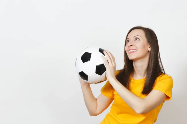 Belle jeune européenne joyeuse femme heureuse, fan de football ou joueur en uniforme jaune tenant ballon de football isolé sur fond blanc. Sport, football, santé, mode de vie sain . — Photo