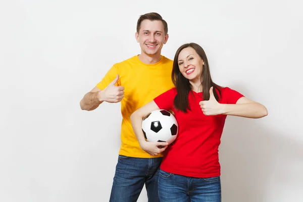 Diversión sonriente joven pareja alegre, mujer, hombre, aficionados al fútbol en uniforme amarillo y rojo animar a equipo de apoyo sosteniendo pelota de fútbol aislado sobre fondo blanco. Deportes, ocio familiar, concepto de estilo de vida . —  Fotos de Stock