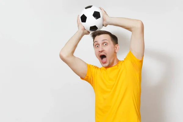 Inspireret ung munter europæisk mand, fan eller spiller i gul uniform hold fange fodbold, juble favorit fodboldhold isoleret på hvid baggrund. Sport spille fodbold, sund livsstil koncept . - Stock-foto