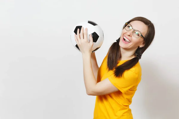 Mujer europea sonriente, dos colas de caballo de la diversión, ventilador de fútbol o jugador en gafas, uniforme amarillo sostienen pelota de fútbol clásico aislado sobre fondo blanco. Deporte, juego, fútbol, concepto de estilo de vida saludable . — Foto de Stock