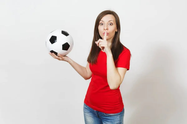 Giovane donna, tifoso di calcio o giocatore in uniforme rossa tenere palla da calcio, dire silenzio con il dito sulle labbra gesto isolato su sfondo bianco. Sport, calcio, tifo, sano concetto di stile di vita . — Foto Stock