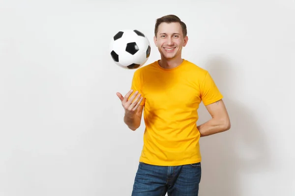 Ispirato giovane allegro uomo europeo, tifoso o giocatore in uniforme gialla vomitare pallone da calcio, tifo squadra di calcio preferita isolata su sfondo bianco. Sport, calcio, stile di vita sano . — Foto Stock