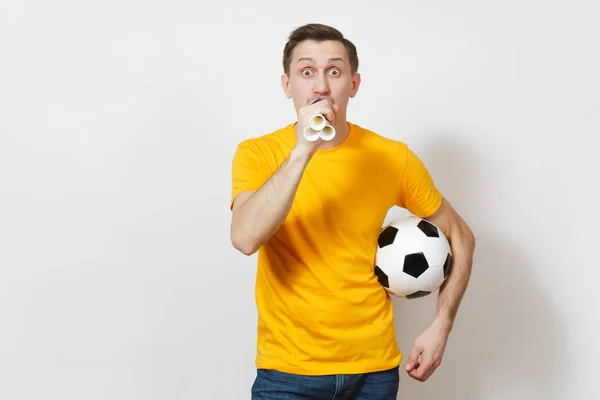 Ispirato giovane divertente allegro uomo europeo, tifoso o giocatore in uniforme gialla tenere palla da calcio, tubo, tifo squadra di calcio preferito isolato su sfondo bianco. Sport, calcio, lifestyle concept . — Foto Stock