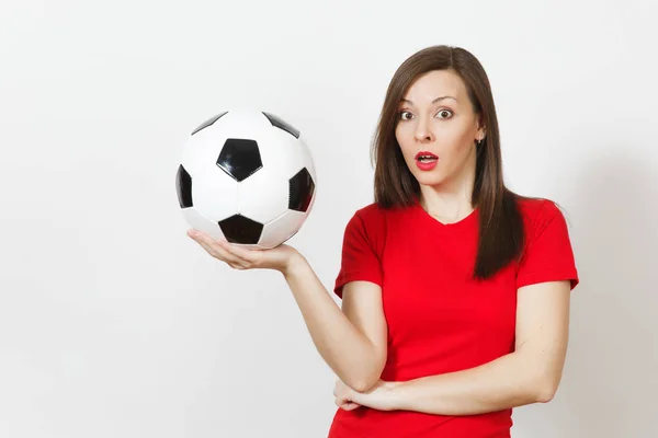Pretty European young sad upset woman, football fan or player in red uniform holds soccer ball, worries about losing team isolated on white background. Sport, play football, lifestyle concept.