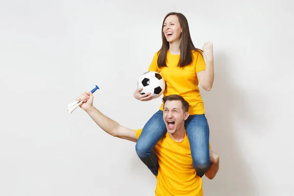 Jeune couple inspiré, femme assise sur les épaules de l'homme, fans avec ballon de football pipe acclamer équipe de football préférée mains gesticulées expressives isolées sur fond blanc. Loisirs en famille, concept lifestyle . — Photo