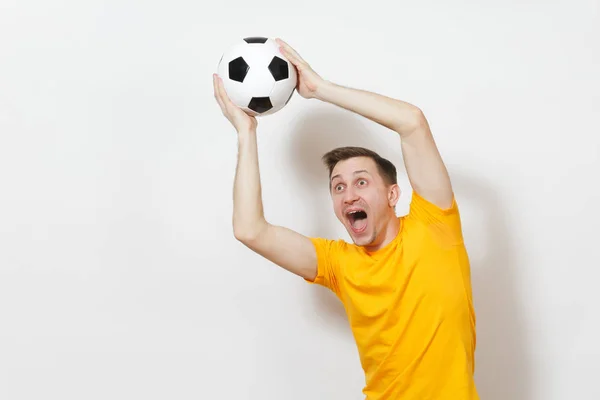 Вдохновленный молодой веселый европейский человек, фанат или игрок в желтой форме держать поймать футбольный мяч, приветствовать любимую футбольную команду изолированы на белом фоне. Спорт играть в футбол, здоровый образ жизни . — стоковое фото