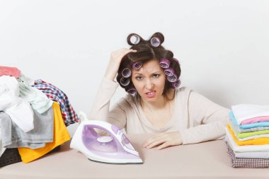 Curlers saç ışık giyim aile giyim Ütü Masası üzerine demir ile Ütü ile sıkıntılı ev kadını. Beyaz arka plan üzerinde izole kadın. Temizlik kavramı. Kopya alanı reklam için.