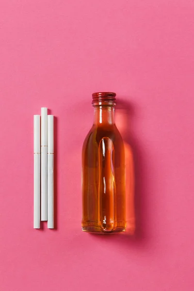 Tres cigarrillos blancos, botella con alcohol coñac, whisky sobre fondo rosa. Salud, elección, concepto de estilo de vida saludable. Copia espacio para la publicidad. Con lugar para el texto . — Foto de Stock