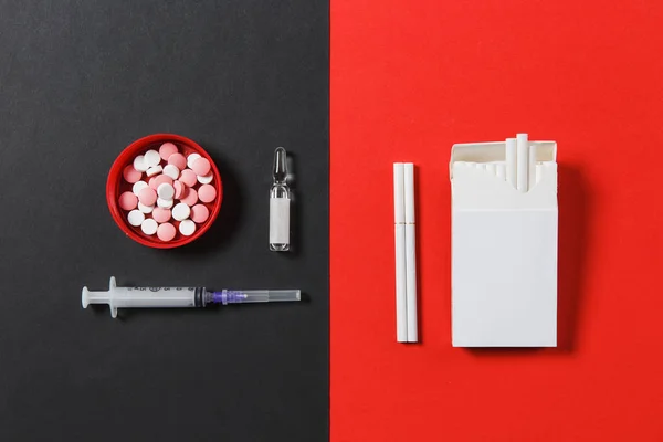 Medicinering färgglada runda tabletter piller, Töm sprutans nål, ampull, pack cigaretter på svart röd bakgrund. Behandling val hälsosam livsstil. Kopiera utrymme för annonseringen. Med plats för text. — Stockfoto