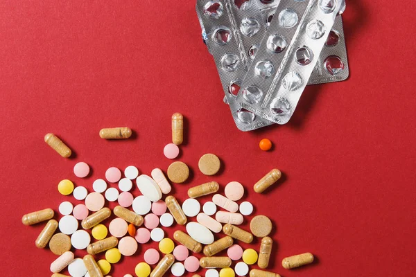 Medicamento blanco colorido redondo tabletas dispuestas abstracto sobre fondo de color rojo. Aspirina, pastillas para cápsulas, envases vacíos. Tratamiento de la salud, elección concepto de estilo de vida saludable. Copiar anuncio de espacio . — Foto de Stock