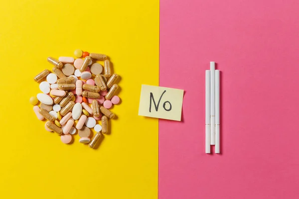 Gyógyszert fehér színes kerek tabletta tabletták rendezett absztrakt három cigaretta a sárga színű háttér. Papír matrica lap szöveg szó nincs. A kezelés választás egészséges életmód fogalma. Másolja a hely. — Stock Fotó