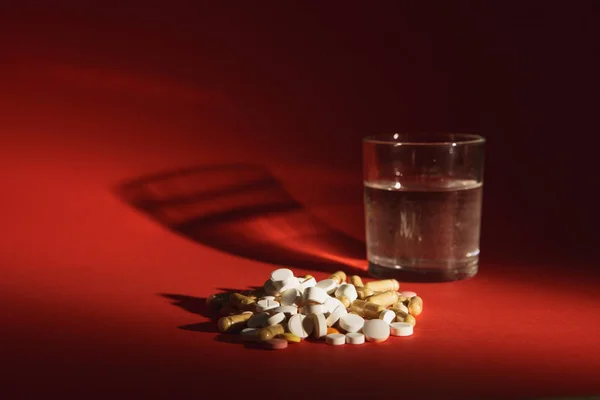 Медикаменти білих барвистих таблеток розташовані абстрактним на темно-червоному тлі. Капсульне флаконове скло з водяних таблеток. Медичне лікування вибір концепції здорового способу життя. Копіювати рекламу простору . — стокове фото