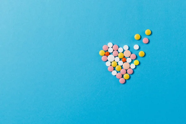 Лекарства красочные круглые таблетки в виде диффузии сердца изолированы на синем фоне. Таблетки. Выбирайте здоровый образ жизни. Копировать космическую рекламу. С местом для текста . — стоковое фото