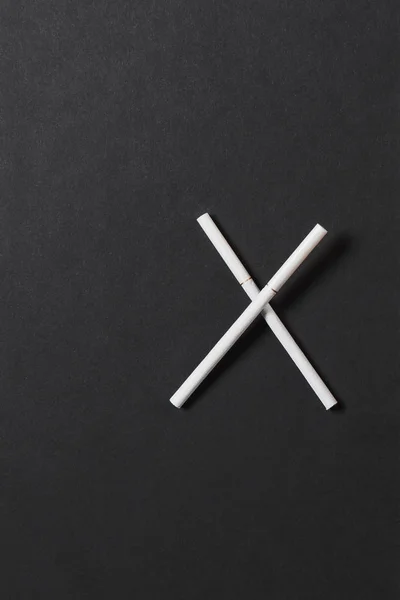 Дві схрещені білі сигарети, такі як літери X на чорному тлі. Здоров'я, вибір, концепція здорового способу життя. Копіювати простір для реклами. З місцем для тексту. Зупинити дим . — стокове фото