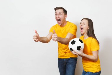 Eğlenceli deli neşeli duygusal genç çift, kadın, erkek, futbol taraftarları destek ekibi ile futbol topu beyaz arka plan üzerinde izole sarı üniforma neşelen. Spor, Aile Eğlence, yaşam kavramı.