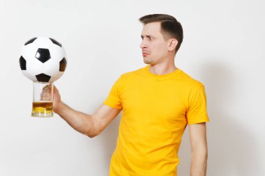 İlham genç eğlenceli Avrupa adam, fan veya oyuncu sarı üniforma tutun bira kupa bira, futbol topu tezahürat favori futbol takımı beyaz arka plan üzerinde izole şok. Spor, oyun, yaşam kavramı.