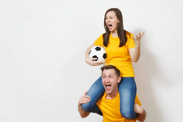 Натхненна молода пара, жінка сидить на людських плечах, фанати з футбольним м'ячем підбадьорюють улюблену футбольну команду, виражаючи жестикулюючі руки ізольовані на білому тлі. Сімейне дозвілля, концепція способу життя . — стокове фото