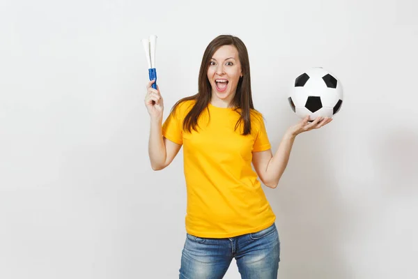 Beautiful European young cheerful happy woman, soccer fan or player in yellow uniform holding football pipe, ball isolated on white background. Sport, play football, health, healthy lifestyle concept.