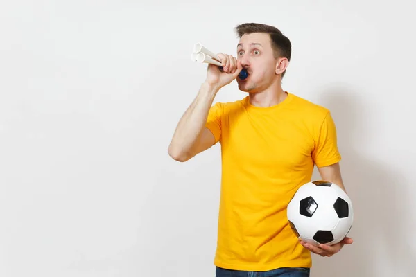 Ispirato giovane divertente allegro uomo europeo, tifoso o giocatore in uniforme gialla tenere palla da calcio, tubo, tifo squadra di calcio preferito isolato su sfondo bianco. Sport, calcio, lifestyle concept . — Foto Stock