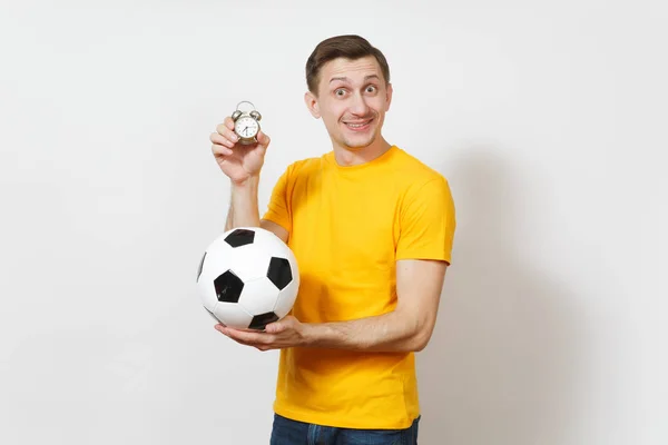 Ispirato giovane allegro uomo europeo, fan o giocatore in uniforme gialla tenere palla da calcio, vecchia sveglia, tifo squadra preferita isolata su sfondo bianco. Sport, calcio, lifestyle concept . — Foto Stock
