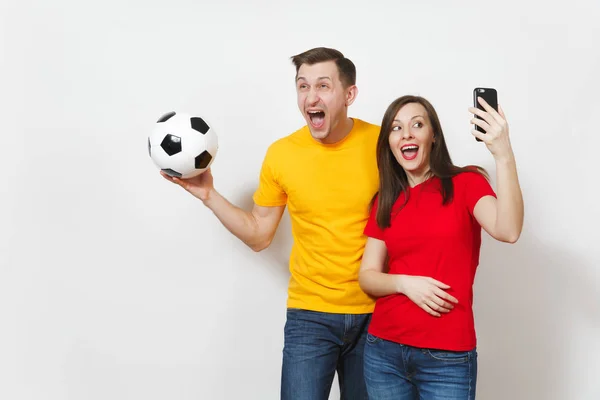 Fotbaloví fanoušci povzbudit tým podpory s fotbalovým míčem izolovaných na bílém pozadí, zábavné šílený kámo mladý pár, muž, Žena, která dělá selfie na mobilním telefonu. Sportovní, rodinné rekreační, stylu života. — Stock fotografie
