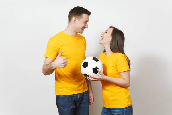 Diversión sonriente alegre joven pareja emocional, mujer, hombre, aficionados al fútbol en uniforme amarillo animar equipo de apoyo con pelota de fútbol aislado sobre fondo blanco. Deportes, ocio familiar, concepto de estilo de vida . —  Fotos de Stock