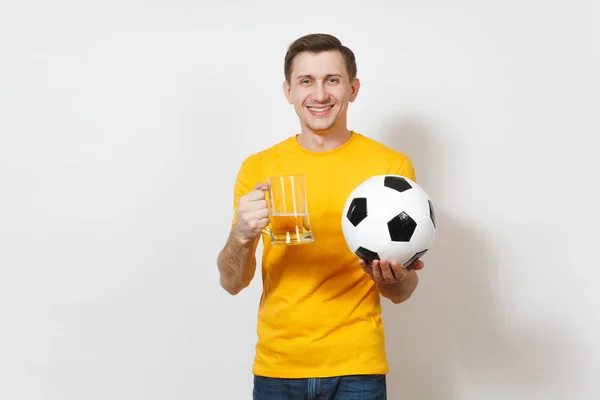 Inspirado joven sonriente hombre europeo, ventilador o jugador en uniforme amarillo sostener jarra de cerveza, pelota de fútbol animar equipo de fútbol favorito aislado sobre fondo blanco. Deporte, juego, estilo de vida concepto . — Foto de Stock