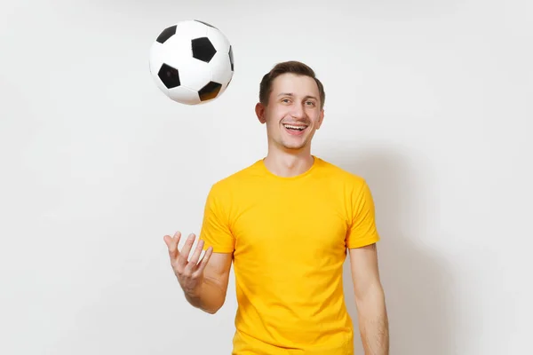 Ispirato giovane allegro uomo europeo, tifoso o giocatore in uniforme gialla vomitare pallone da calcio, tifo squadra di calcio preferita isolata su sfondo bianco. Sport, calcio, stile di vita sano . — Foto Stock