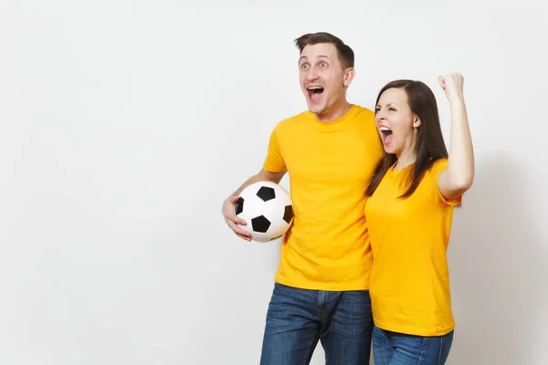 Diversión loca alegre joven pareja emocional, mujer, hombre, aficionados al fútbol en uniforme amarillo animar equipo de apoyo con pelota de fútbol aislado sobre fondo blanco. Deportes, ocio familiar, concepto de estilo de vida . —  Fotos de Stock