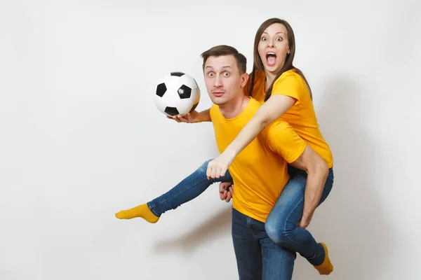 Jeune couple inspiré, femme assise sur le dos de l'homme, fans avec ballon de football acclamant l'équipe de football préférée mains gesticulantes expressives isolées sur fond blanc. Loisirs en famille, concept lifestyle . — Photo