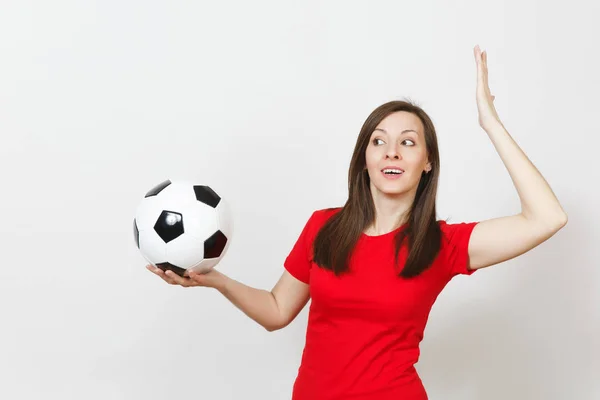 Attractive European young cheerful smiling woman, football fan or player in red uniform holding soccer ball isolated on white background. Sport, play football, cheer, healthy lifestyle concept.